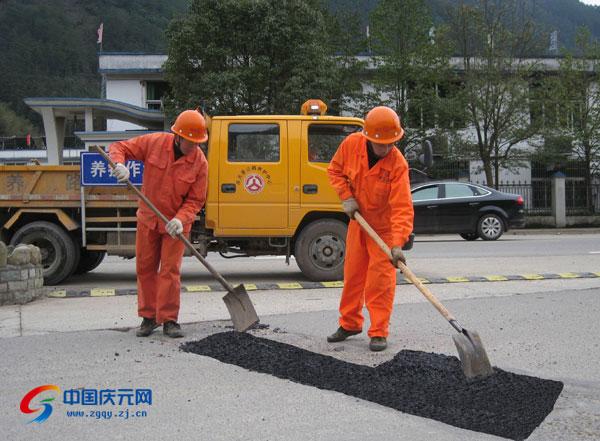 图为公路养护人员在修补路面坑洞